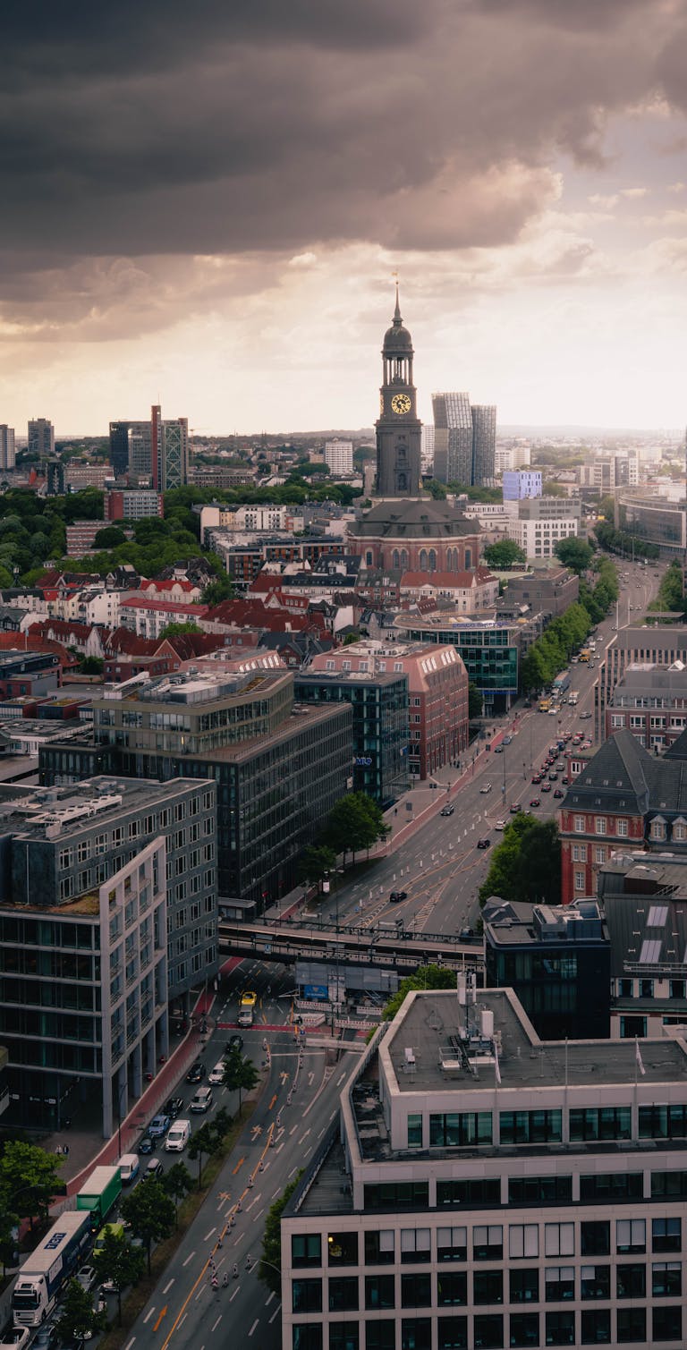 A stunning aerial view of a cityscape with a prominent clock tower under dramatic skies at sunset.