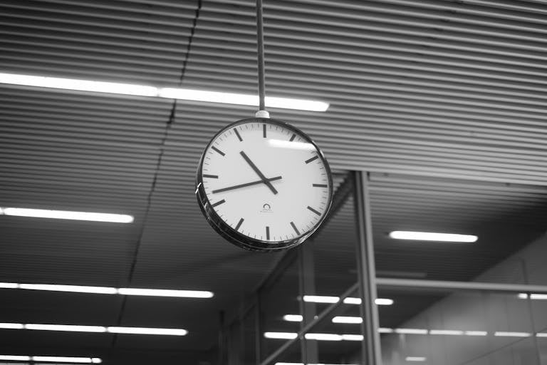 Black and white image of a modern hanging clock in an indoor setting in Krakow, Poland.